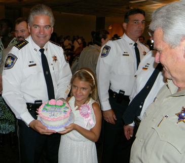  The sheriff's daughter, Victoria, celebrates her 8th birthday with a cake at the reception  after her father is sworn in. 