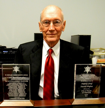Deputy Chief Harold Hughes, who has handled the Internal Affairs duties of the St. Bernard Sheriff’s Office for 28 years, holds two plaques presented him by Sheriff James Pohlmann at a retirement ceremony. 