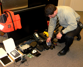 Sheriff’s Det. Trey Delaune looks over property recovered in Vaughn’s arrest. 