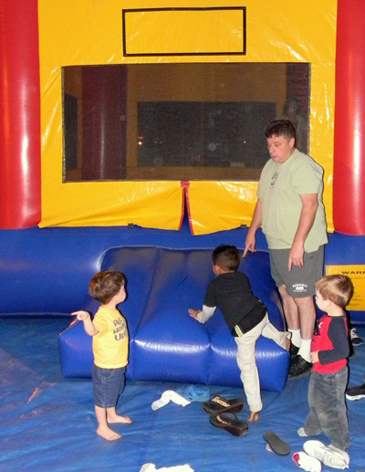 Children take off their shoes to enter a bounce tent at a party. 