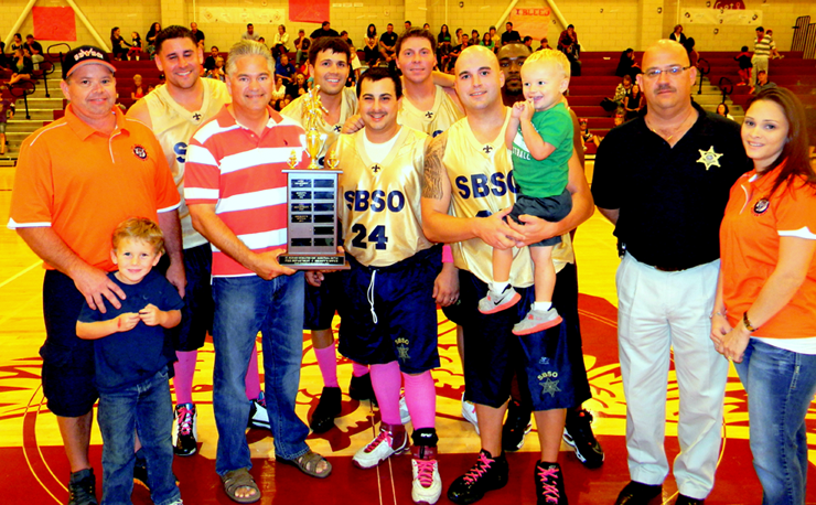 Dwayne Gref and his son, Gavin; Sheriff James Pohlmann holding the trophy presented to the winning Sheriff's Office team, Justin Topey, Brad Nuccio holding son, Brayden, Coach Col. David Mowers, Amanda Mones of Gulf Coast Bank; and in back Ryan Laylle, Brandon Licciardi, Jonathan Smith and Shelton Smith.