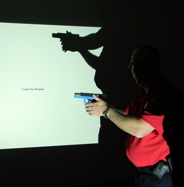 Maj. David DiMaggio, head of training for the Sheriff’s Office is shown in silhouette against a screen used in the firearms simulator program as he explains the device for participants in the Citizens Police Academy class.