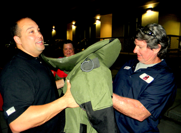 Gerald Grosch of Meraux, at right, is handed a 90-pound bomb squad jacket from Sgt. Stephen Ingargiola during a display of bomb squad equipment.