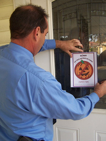 St. Bernard Sheriff's Detective Lt. Richard Mendel places a flier on the door of a registered sex offender in October 2011 to remind them they are prohibited by law from giving out candy or gifts to minors on Halloween.