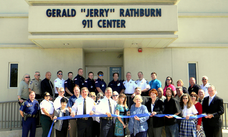 Trudy Rathburn, on front row and has white hair, cuts the ribbon at the dedication and renaming of the parish 911 Center in the name of her deceased husband, sheriff’s Col. Gerald “Jerry’’ Rathburn who died of an illness last April 21. He is credited as the driving force behind St. Bernard’s modern 911 emergency system. 