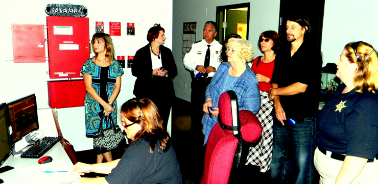 Trudy Rathburn, in blue dress, stands among a group of family members who toured the inside of the 911 Center with Sheriff James Pohlmann after the ceremony renaming the building in honor of her deceased husband, sheriff’s Col. Jerry Rathburn. 