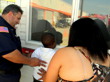 Chase Aronolie, with mother Krystal Aranolie who works in Chalmette, gets a boost up from Fire Dept. Capt. Rory Miller to look into the Fire Safety House used to teach  children how to drop and roll on the floor to escape a burning building in thick smoke.