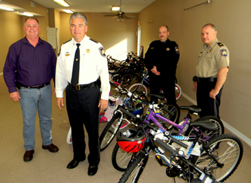 Sheriff James Pohlmann and, to his right, Daniel Talley Sr., Operations Manager for Associated Terminals, with the 24 bicycles the company donated to the Sheriff's Office to distribute to needy families for Christmas. Behind them are, from left, Maj. Kevin Sensebe and Capt. Adrian Chalona, who took part in the bicycles project. 