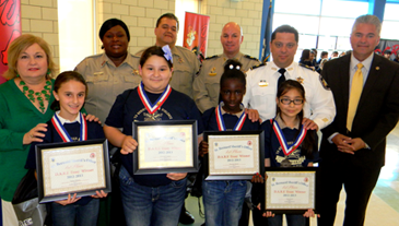 Winners of the D.A.R.E. essays at Arabi Elementary are, in front row: Taylor Hebert, Dawnell Conley, Kennise Baker and Katie Jovel. In the back are Principal Carla Carolla, Lt. Lisa Jackson, Sgt. Darrin Miller, Capt. Ronnie Martin, Maj. Chad Clark and Sheriff  James Pohlmann.