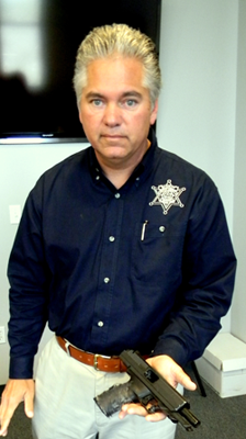 Sheriff James Pohlmann holds the gun which has obliterated serial numbers and notches carved into 