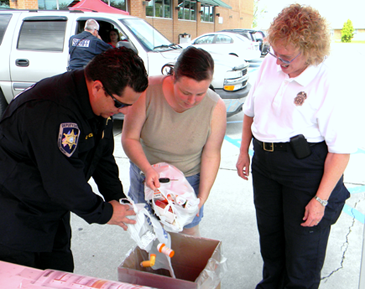 Jennifer Landry of Chalmette empties old prescription medications in a collection box on April 27. With her are Maj. Chad Clark and Lt. Pat Childress of the Sheriff's Office. 