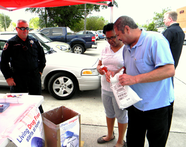 A couple gets rid of their old medications. At left is Sgt. Joey Alfonso and at right is Bill Hagoort , district manager for Walgreen. 