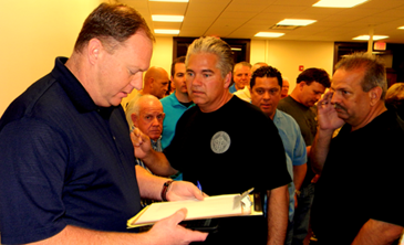 John Vickers, left, of the Sheriff's Office and Sheriff James Pohlmann go over voting returns coming in at the Clerk of Court's Office after the millage election, as deputies crowd the office awaiting results. 