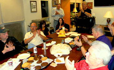 Sheriff Pohlmann, standing at right, applauds with others in the conference room at the Sheriff's Office as they watch final results from the millage election flash on a television screen.