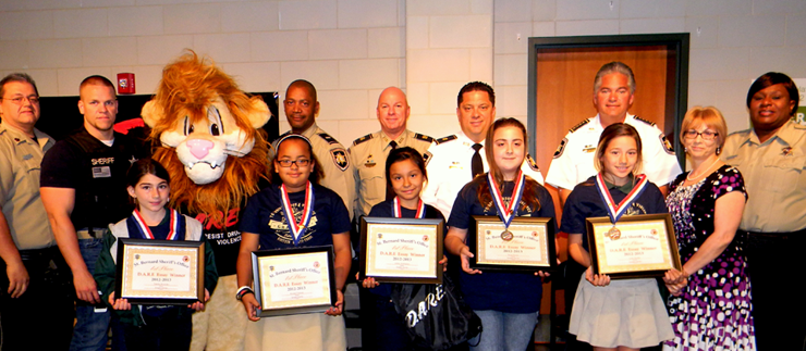 D.A.R.E. essay winners at Joseph Davies School are, from left, Tabitha Bruscato, Krystal Vicknair, Ashley Rodriguez, Sarah Borne, Leah Abadie and with them, Principal Donna Schultz. In back row are Sgt. Darrin Miller, Agent Daniel Bostic, Cpl. Jessica Gernados portraying mascot Daren the Lion, Lt. Ricky Jackson, Capt. ronnie Martin, Maj. Chad Clark, Sheriff James Pohlmann and Lt. Lisa Jackson. 