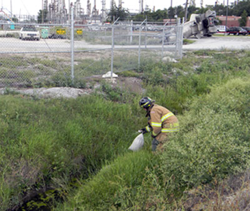 A St. Bernard firefighter places sandbags in the ditch as a precaution in case its water was contaminated by the leaking chemical from the truck, which can be seen in the background.