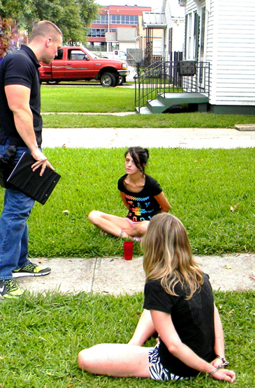 Narcotics Agent Daniel Bostic talks with the suspects on the ground, Rachel Butler in the foreground and Melissa Huy in the background.