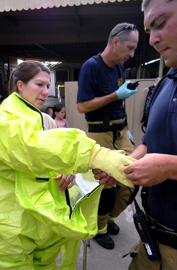 Cpl. Jessica Gernados of the St. Bernard sheriff’s Narcotics Unit puts on a decontamination suit, aided by a parish firefighter, as she prepares to decontaminate three young children who lived in a Chalmette house where a small meth lab was operating in a shed behind the home, authorities said.