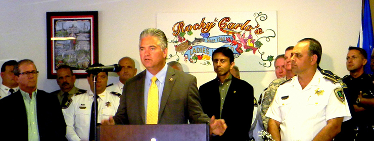 Sheriff Pohlmann speaks at the podium, standing next to Gov. Jindal.