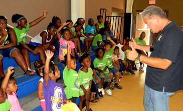 Children at the Christian Fellowship summer camp raise their hands to ask questions of Sheriff James Pohlmann after he spoke to them.