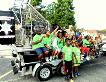 Children signal to their friends as they ride the sheriff's airboat, being demonstrated by Capt. Brian Clark, head of the Marine Division.