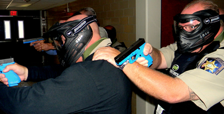 Capt. Ronnie Martin, at bottom left, Capt. Walter Dornan, top left, and Deputy Sheriff Kenny Sierra, behind Martin, wear helmets with a shield to protect their face and eyes as they enter a room where an active-shooter may fire non-lethal, detergent-based simunition ammo training rounds at them.