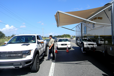 Sheriff's Deputy Henry Senez works a check point in Reggio at the junction to Yscloskey and Delacroix Island in easternmost St. Bernard Parish, which is outside the hurricane protection levee and was the scene of major activity on Friday as people went to remove boats and vehicles from the possible path of the approaching tropical storm.