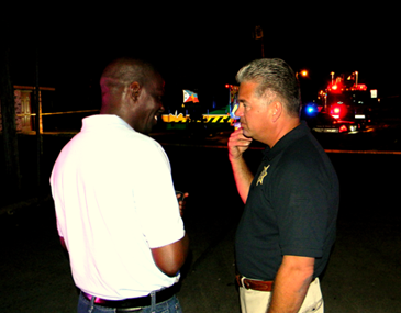 Sheriff James Pohlmann talks with Kevin Gabriel of Violet near the scene of the shooting. 	