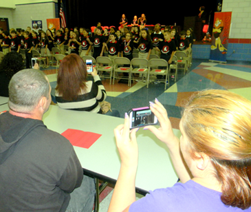 Some of the parents at Gauthier are shown taking videos and photos of their children as they perform the D.A.R.E. theme song.