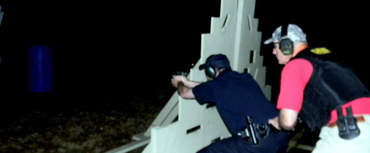 Reserve Division Deputy Sheriff Chris Dupont fires at a target in the dark, with Lt. Raymond Theriot behind him.