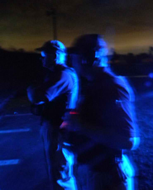 Lt. Raymond Theriot, left, and Training Director Maj. David DiMaggio. in a blue light cast by a patrol car during low light target training.