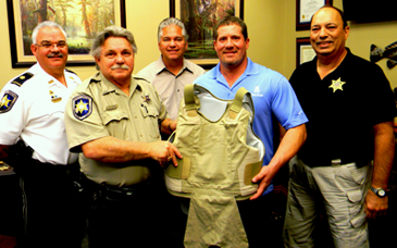 Jason Perez, an operations manager at Associated Terminals, holds a protective body armor vest with Reserve Division Dep. Sheriff Albert Loar, one of four vests the company is donating to the Sheriff's Office for the Reserve Division. Shown behind them are Maj. Mark Poche, at left, Sheriff James Pohlmann and Capt. Charles Borchers. 