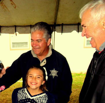 Sheriff James Pohlmann, with daughter Victoria, who danced on the stage with a group from Our Lady of Prompt Succor for the Santa on the Bayou event, talks with Anthony Fernandez Jr., at right, director of the annual festival. 