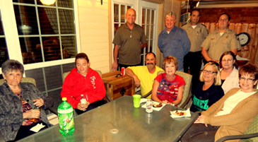 A Night Out Against Crime event at the home of Rosemary Gioe. seated at the top center of the table, in Chalmette. Detective deputies Lt. Richard Mendel and Ryan Melerine. shown in back, were assigned to the event.