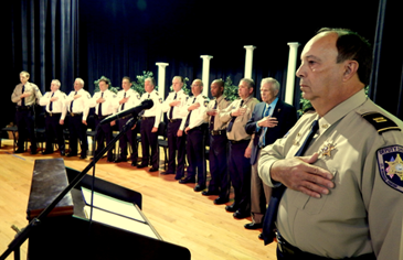 Members of the Sheriff's Office senior staff and Nunez College Chancellor Thomas Warner stand on the stage at Nunez for the playing of the Star Spangled Banner.